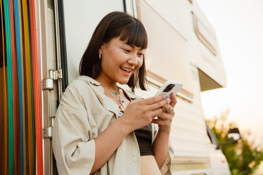 Asian young woman using cellphone while leaning on trailer
