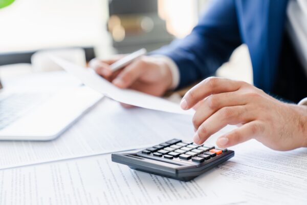 Hombre de negocios contando billetes inversiones ahorros dividendos en la calculadora