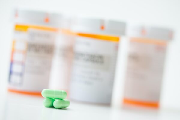 Green capsules in front of orange pharmacy bottles
