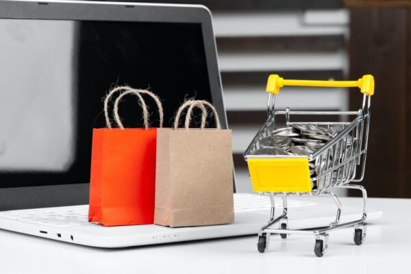 Online-Shopping-Konzept. Einkaufswagen, Laptop auf dem Schreibtisch