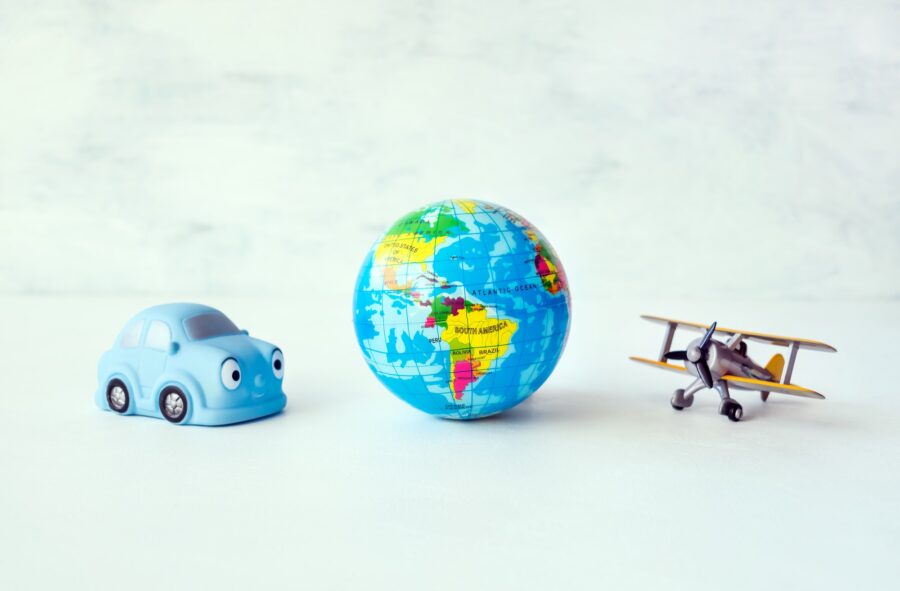 Travel, adventure, vacation concept. Toy yellow air plane, blue car and globe earth ball, map on