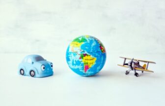 Travel, adventure, vacation concept. Toy yellow air plane, blue car and globe earth ball, map on